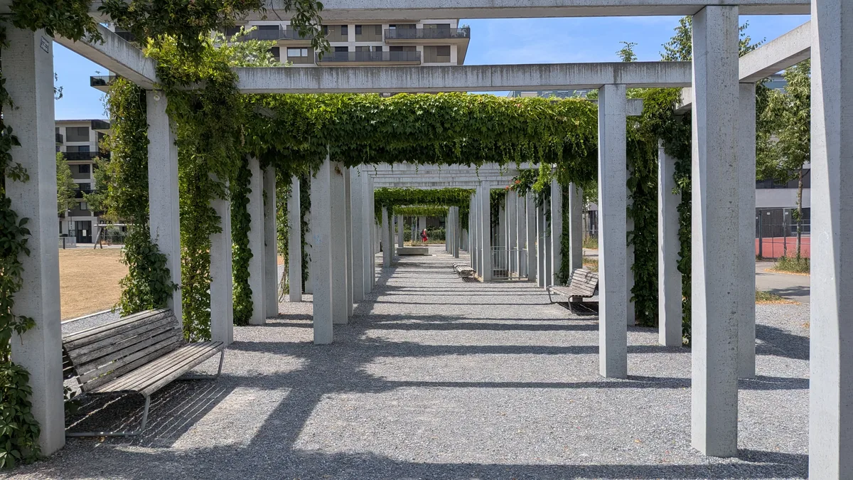 Roher Beton und zartes Grün – ein schöner Kontrast. Für ein Schatten spendendes Dach fehlen allerdings die Querverbindungen zu den Bögen, an denen sich die Pflanzen entlangschlängeln könnten. Impressionen aus einem Park.